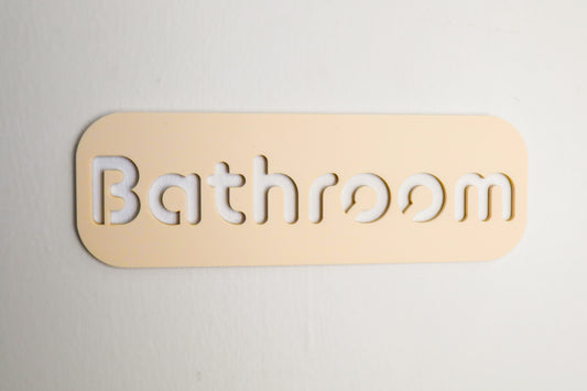 Contemporary beige bathroom door sign with cut-out text and self-adhesive backing for effortless placement