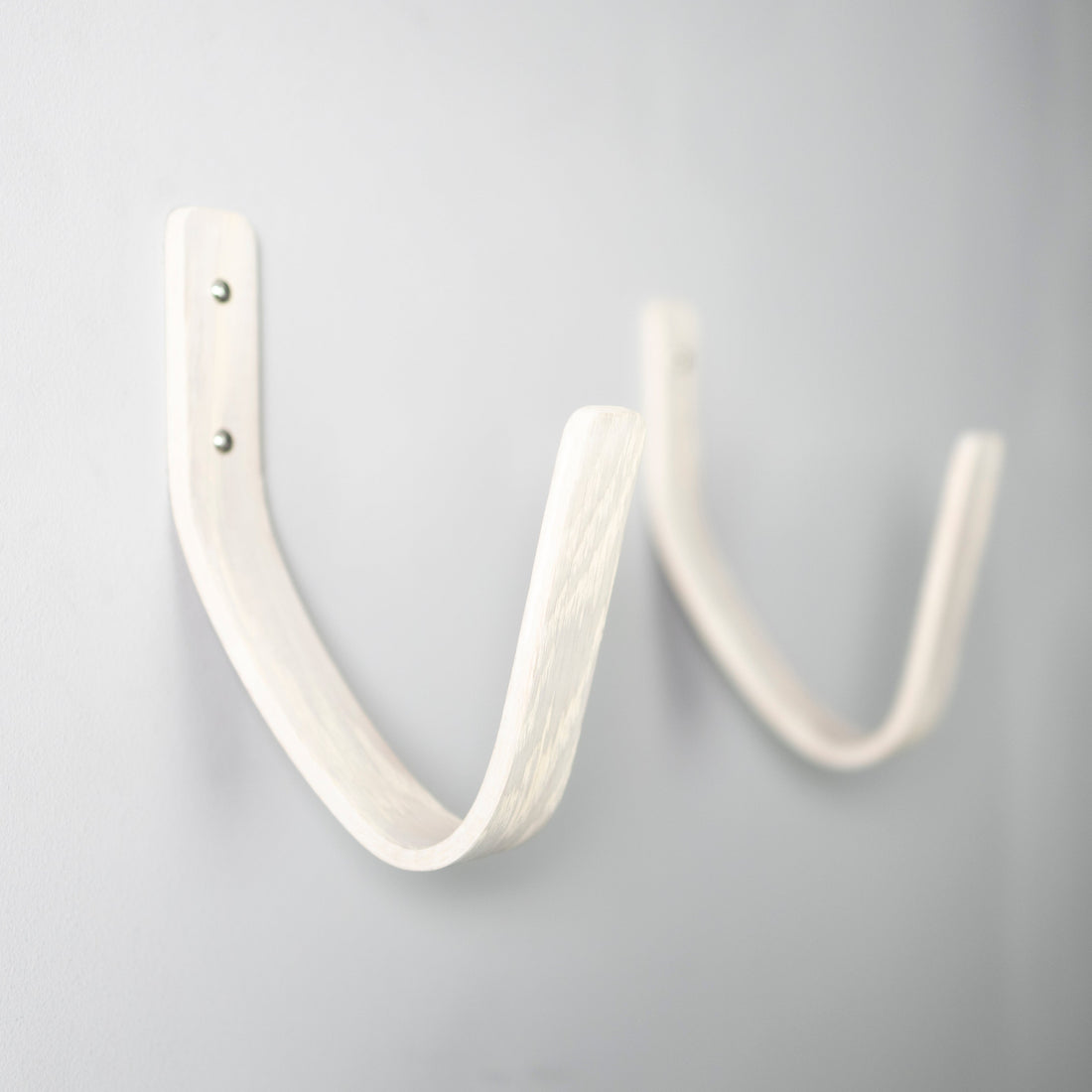 White surfboard wall mount displaying a surfboard in a coastal interior setting