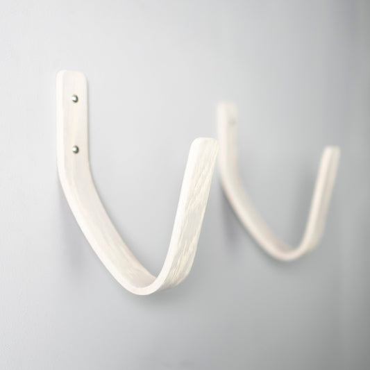 White surfboard wall mount displaying a surfboard in a coastal interior setting
