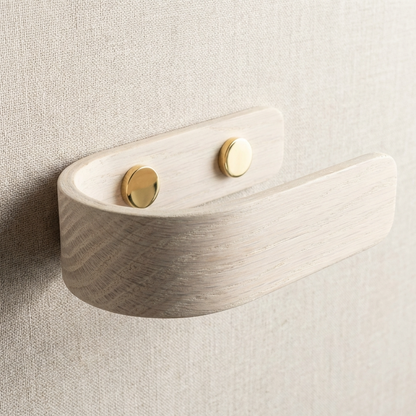 Wooden wall hook with brass circular plates on a neutral background