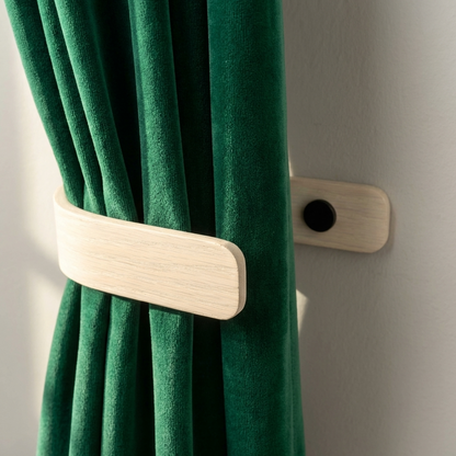 Green curtain with a wooden tieback against a gray wall